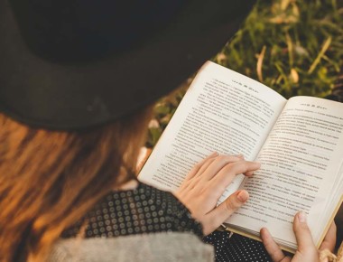 Young person reading a book while sitting outside