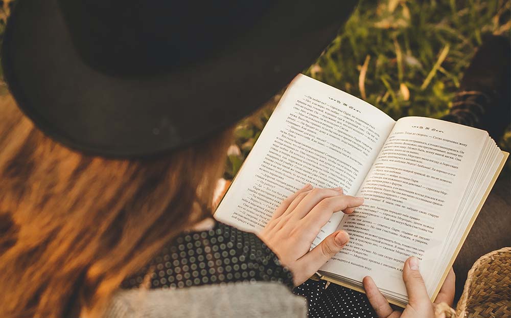 Young person reading a book while sitting outside